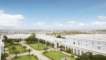 A large white building with a symmetrical courtyard, arched walkways, and a view of a cityscape in the background.