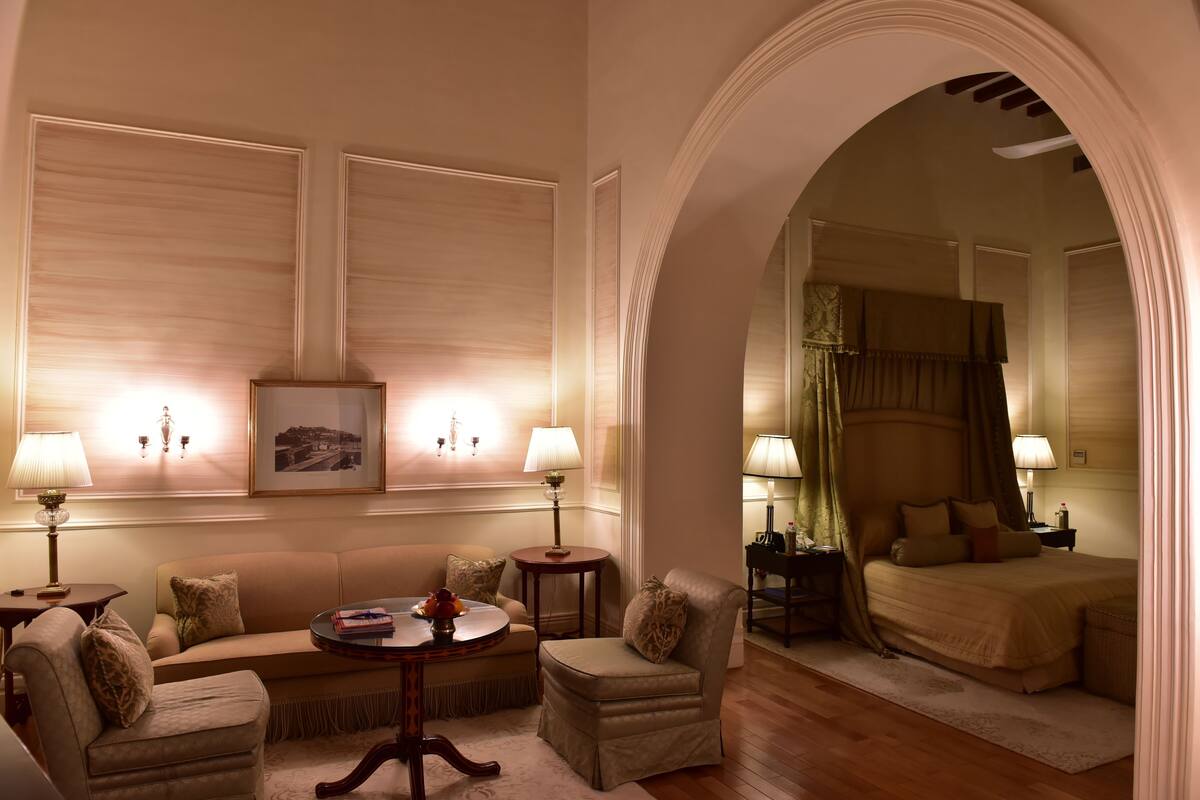 Ein Hotelzimmer mit einer Sofagarnitur, einem runden Couchtisch und einem Bett mit Baldachin.