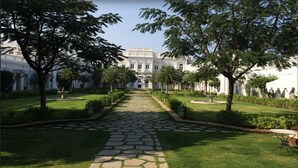 A formal garden with a central pathway leading to a large building with classical architecture. - Taj Falaknuma Palace (Hyderabad)