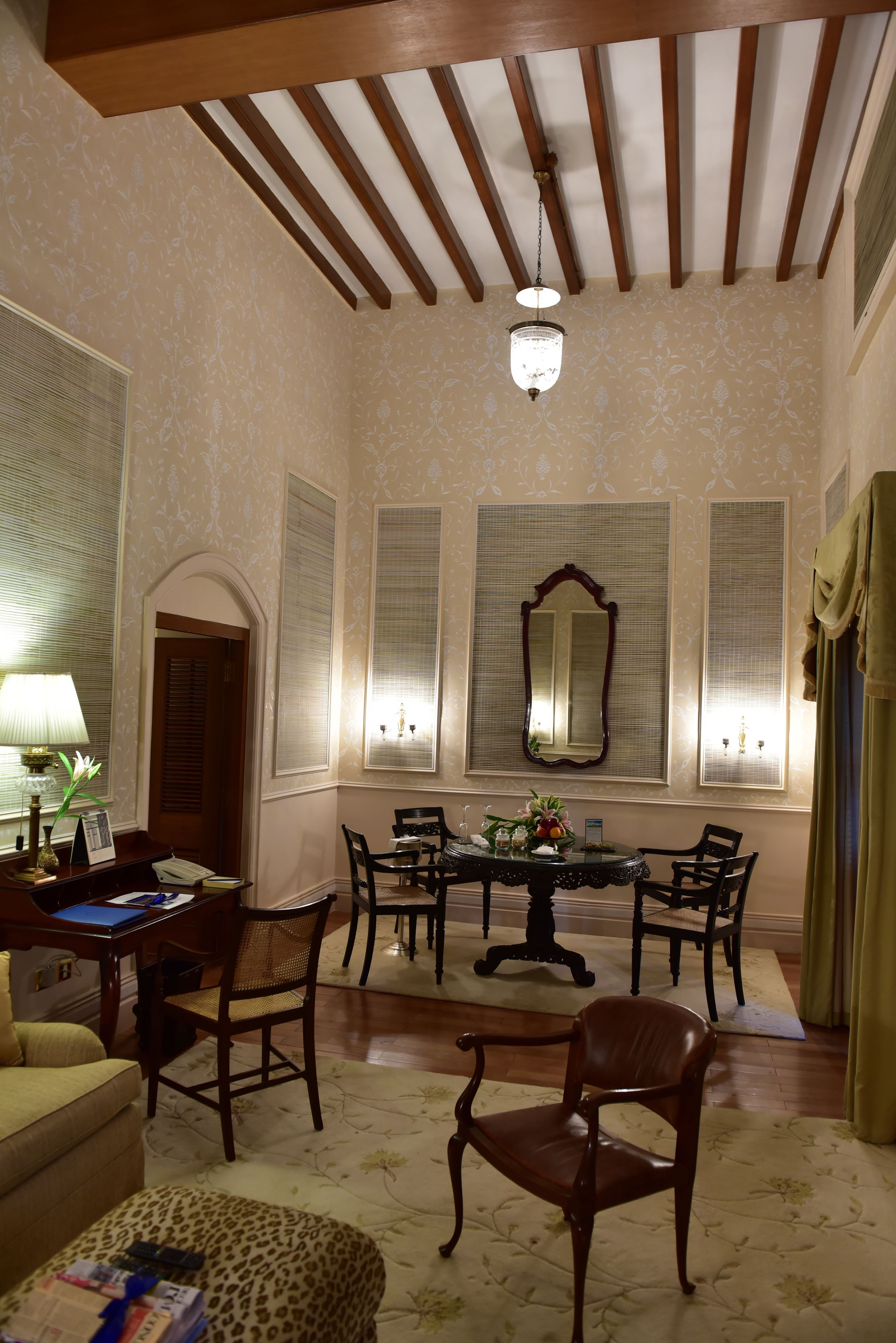 A dining area with a table, chairs, a chandelier, and a mirror on the wall.