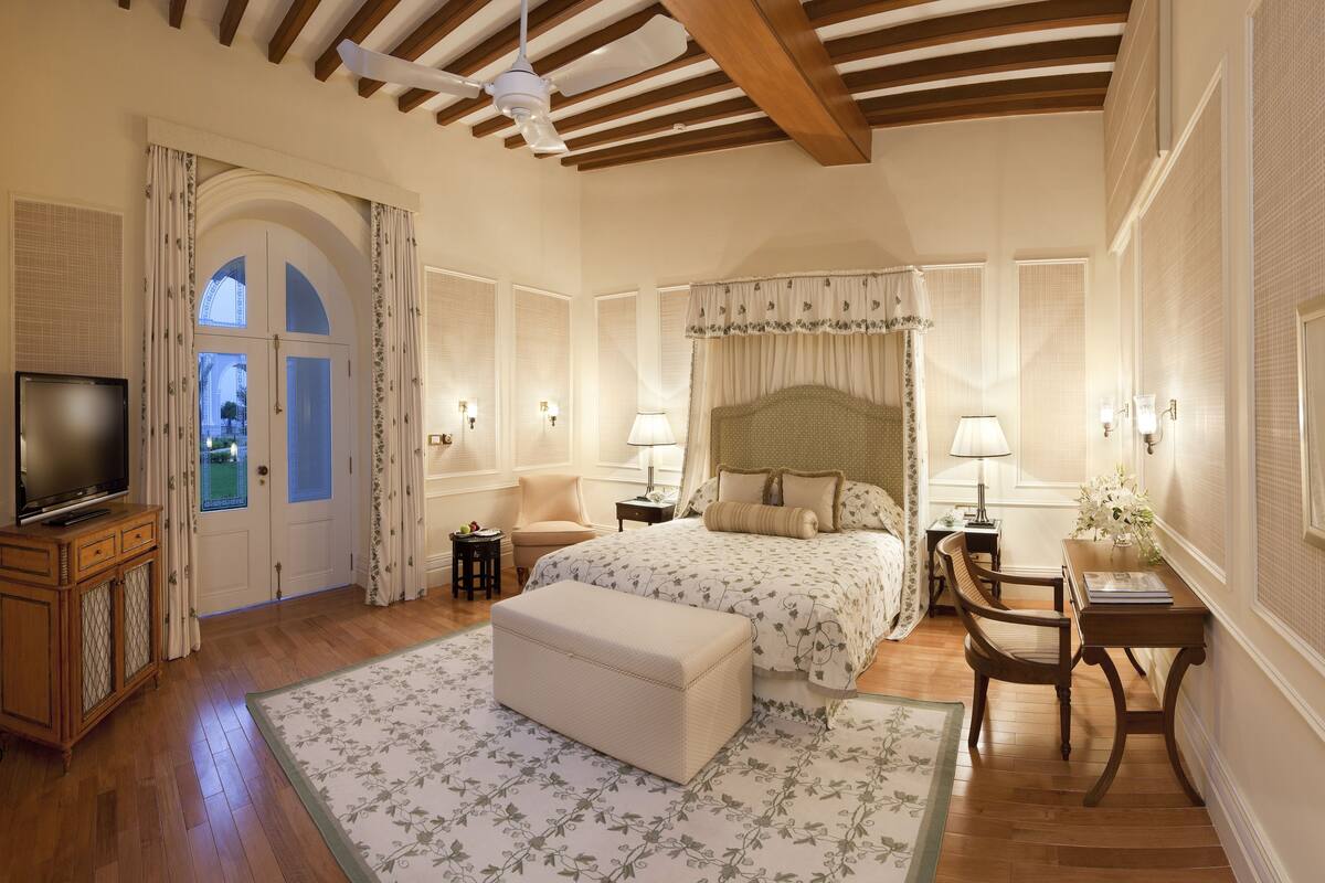 Ein Schlafzimmer mit einem großen Bett, einem Fernseher, einem Schreibtisch und einem Sessel.