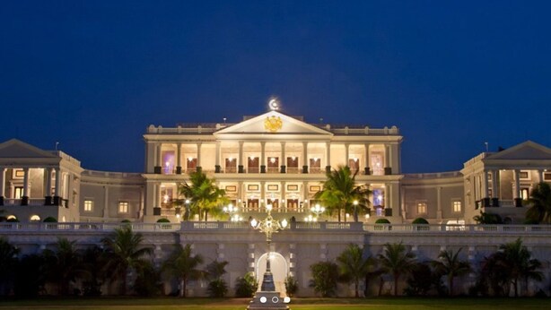 A grand, illuminated building with a central dome and symmetrical wings, featuring a prominent entrance and a well-maintained garden in front. - Taj Falaknuma Palace (Hyderabad)