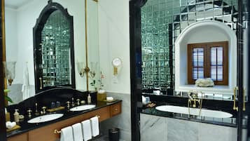 Een luxe badkamer met twee wastafels, een grote spiegel en een raam met houten luiken.