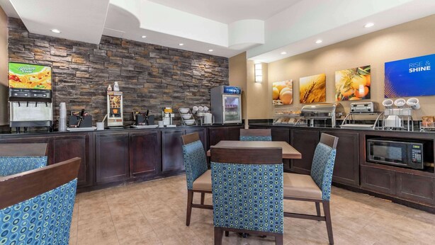 A modern restaurant with a stone wall, a digital menu board, and a microwave. - Comfort Suites Medical Center near Six Flags (San Antonio)
