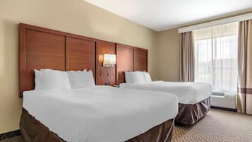 Une chambre d’hôtel avec deux lits, une grande tête de lit en bois, une lampe fixée au mur et une fenêtre avec des rideaux.