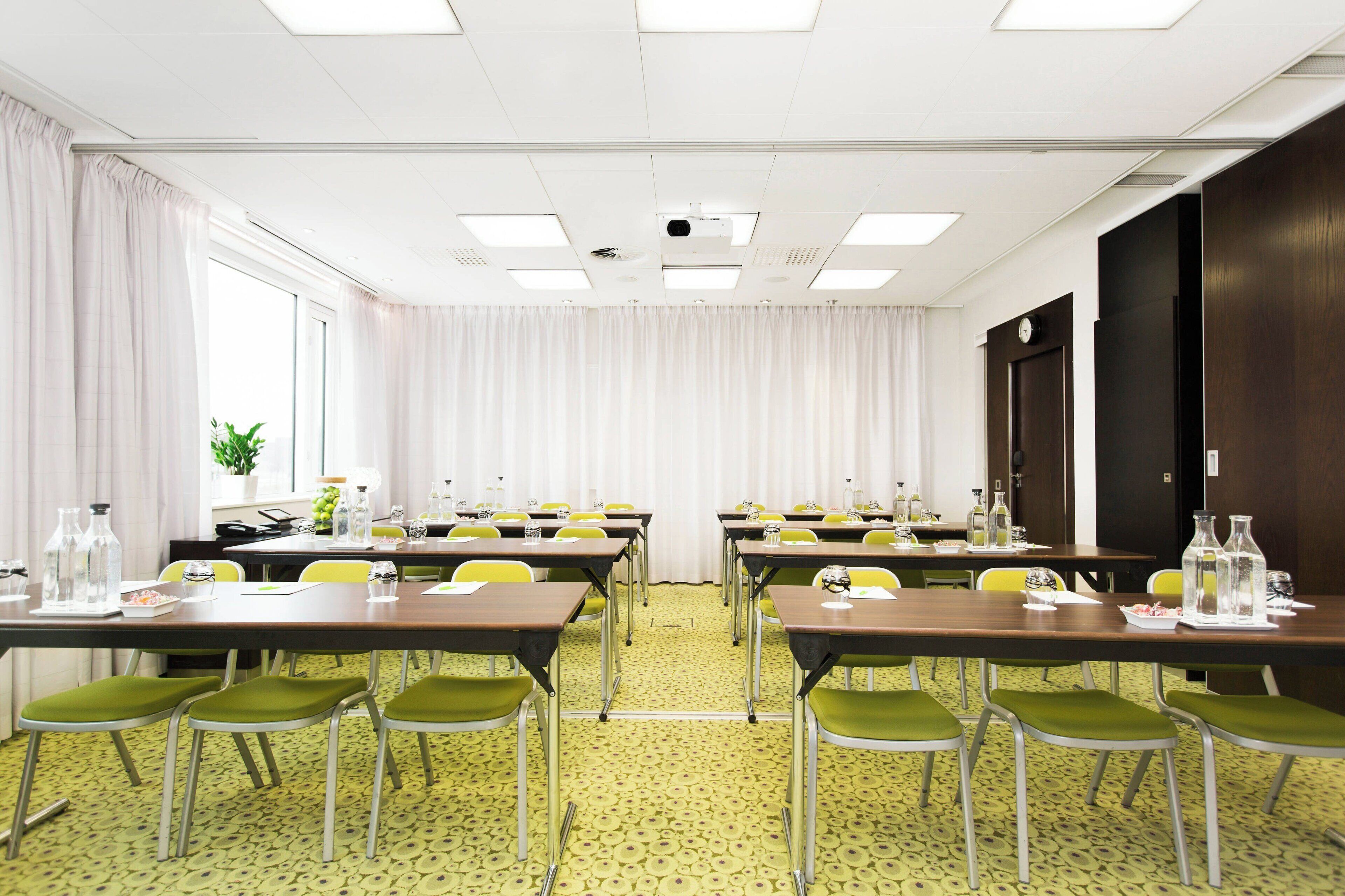 A conference room with tables, chairs, and a projector.