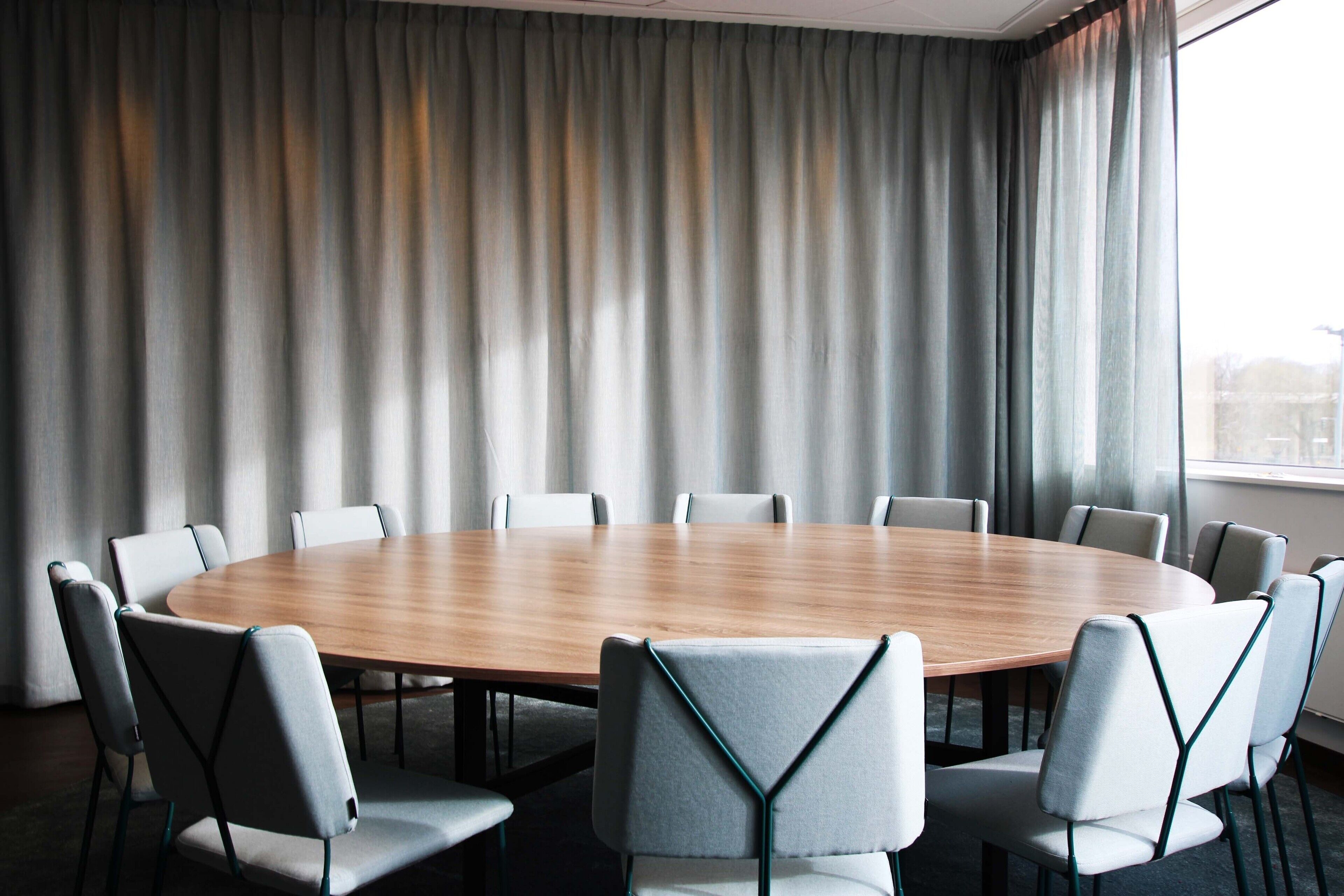 A conference room with a round table and eight chairs.