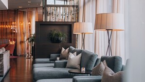 Eine moderne Lounge mit grauen Sofas, einem kleinen Tisch mit einem Glas und zwei Stehlampen.