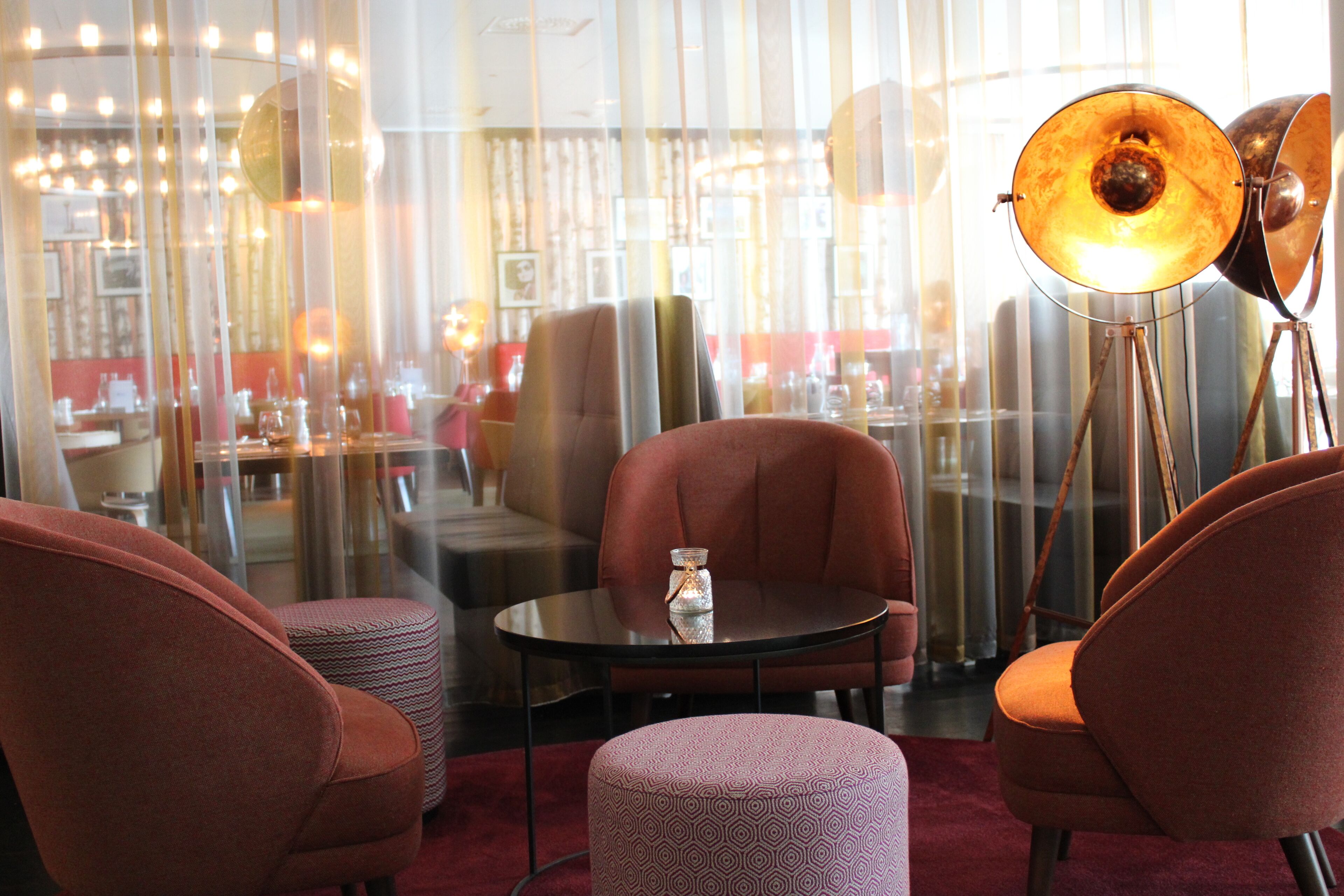 Un intérieur moderne avec une table ronde, deux fauteuils, un lampadaire et un pouf à motifs.