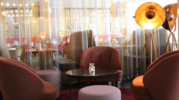A modern interior with a round table, two armchairs, a floor lamp, and a patterned ottoman.