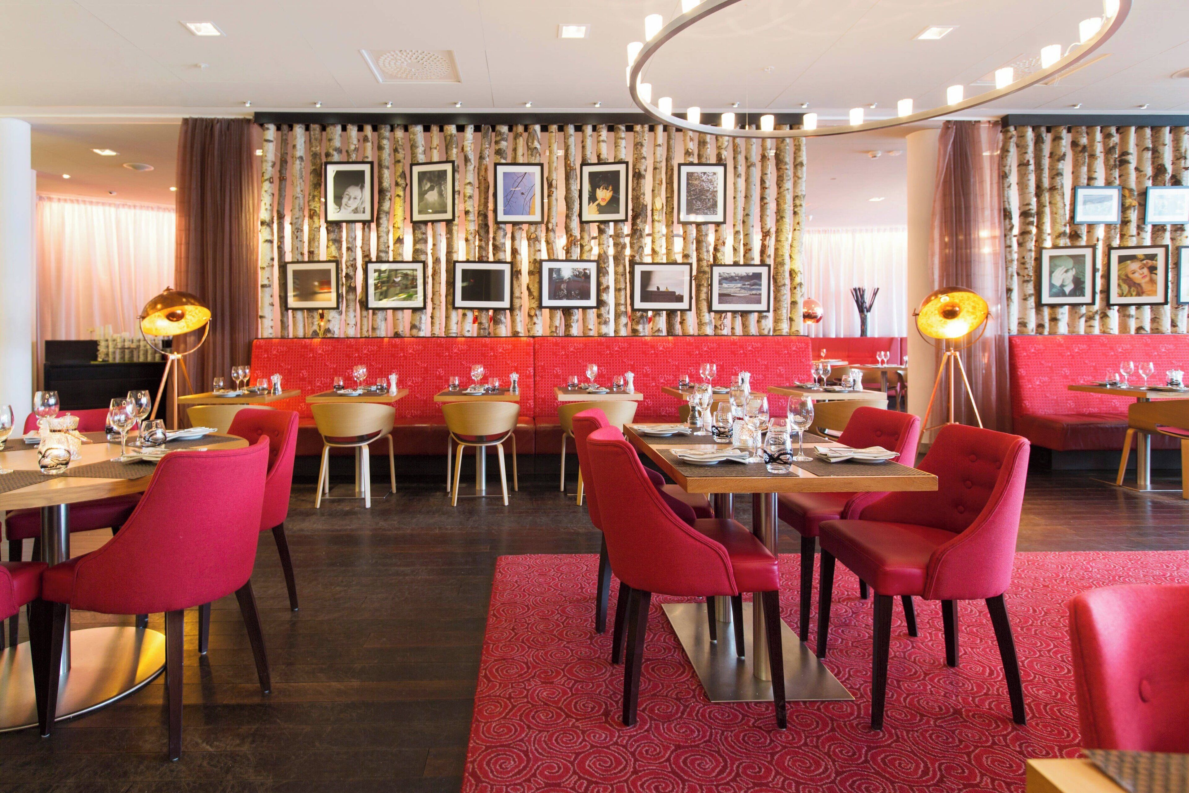 Ein Restaurant mit rot gepolsterten Sitzecken, einer Wand mit gemusterten Bildern und einem roten Teppichboden.