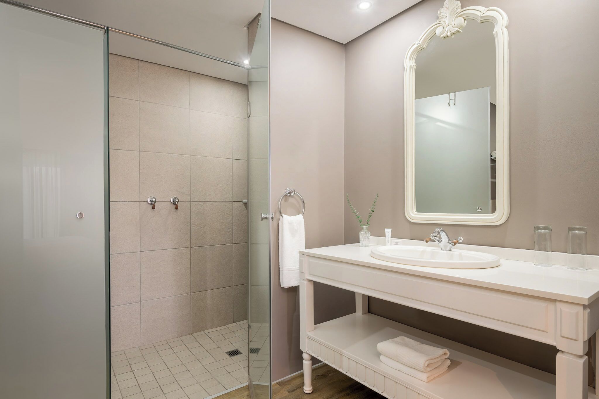Une salle de bain moderne avec une douche à parois de verre, un meuble-lavabo blanc avec un miroir et un évier.
