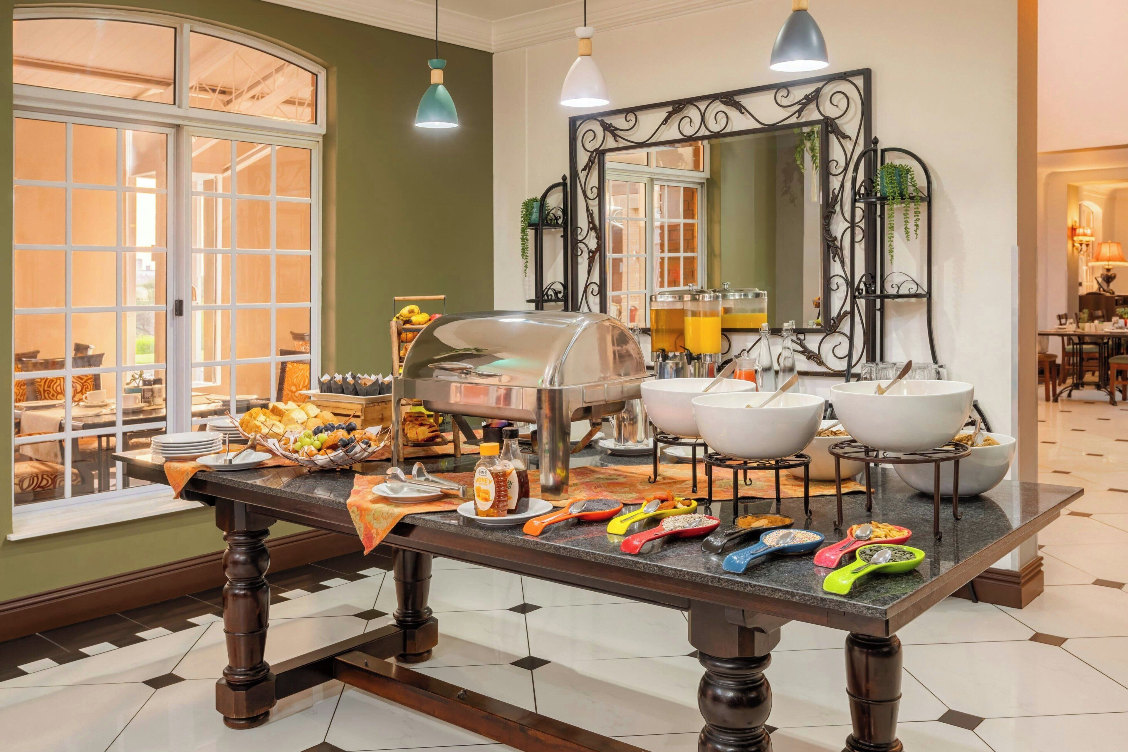 A buffet setup with a variety of food items, a large mirror, and a window with a view of the outside.