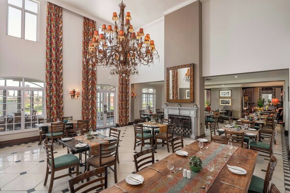 A spacious dining area with high ceilings, a large chandelier, and a view of the outdoors. - Protea Hotel by Marriott Kimberley (Kimberley)