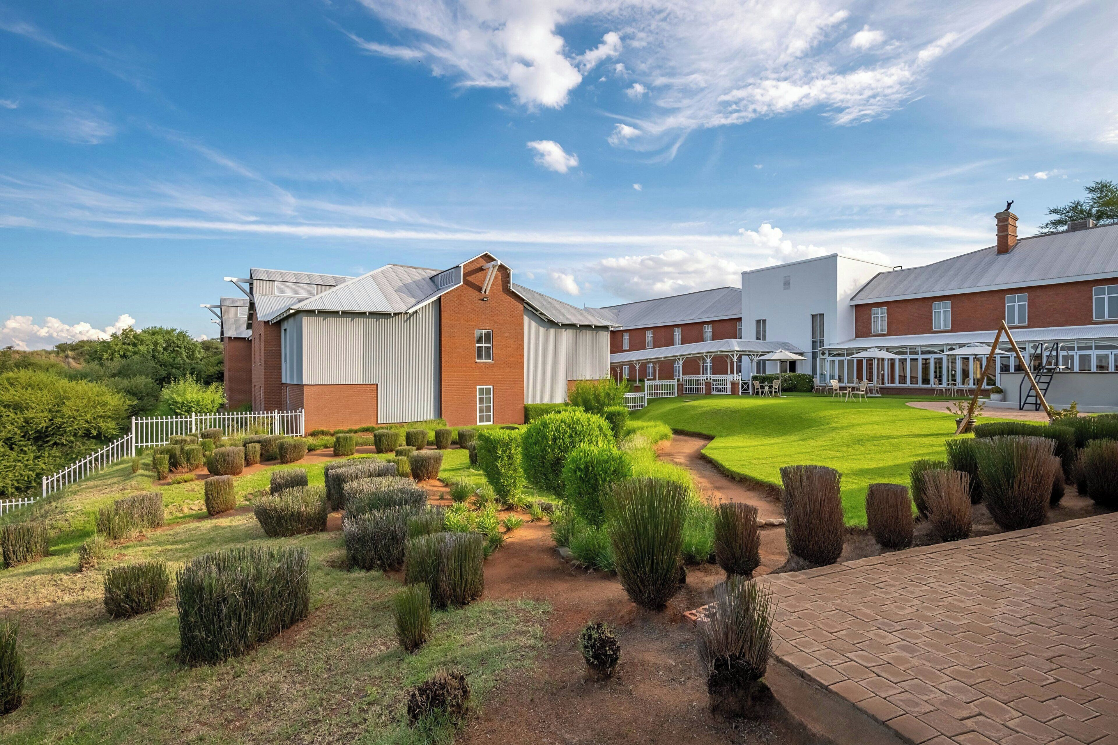A large building with a brick facade and a white exterior, surrounded by well-maintained gardens and a paved walkway.