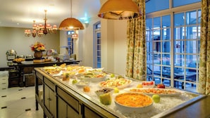 Montaje de bufé con diferentes alimentos, un ventanal con cortinas y un candelabro.