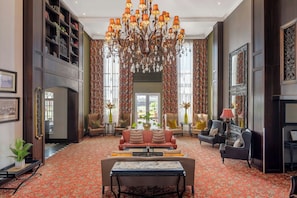 Ein geräumiger Raum mit einem großen Chandelier, mehreren Sitzgelegenheiten und einer Bücherwand.