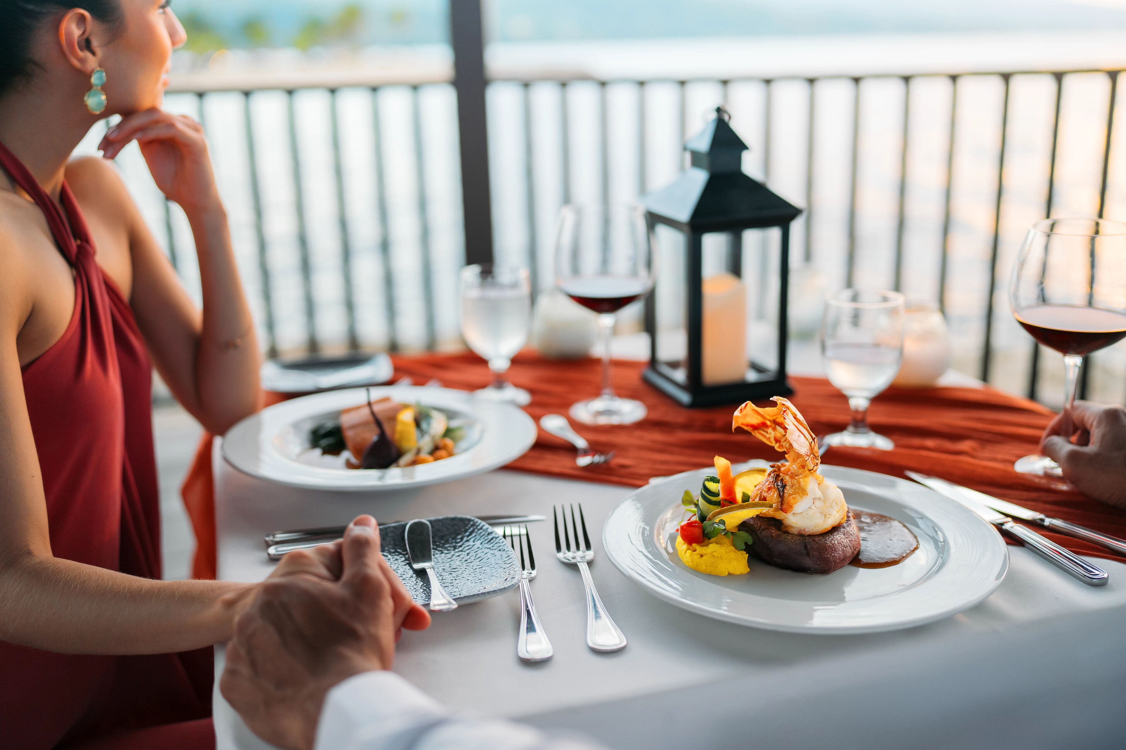 A dining table with plates of food, wine glasses, and cutlery.