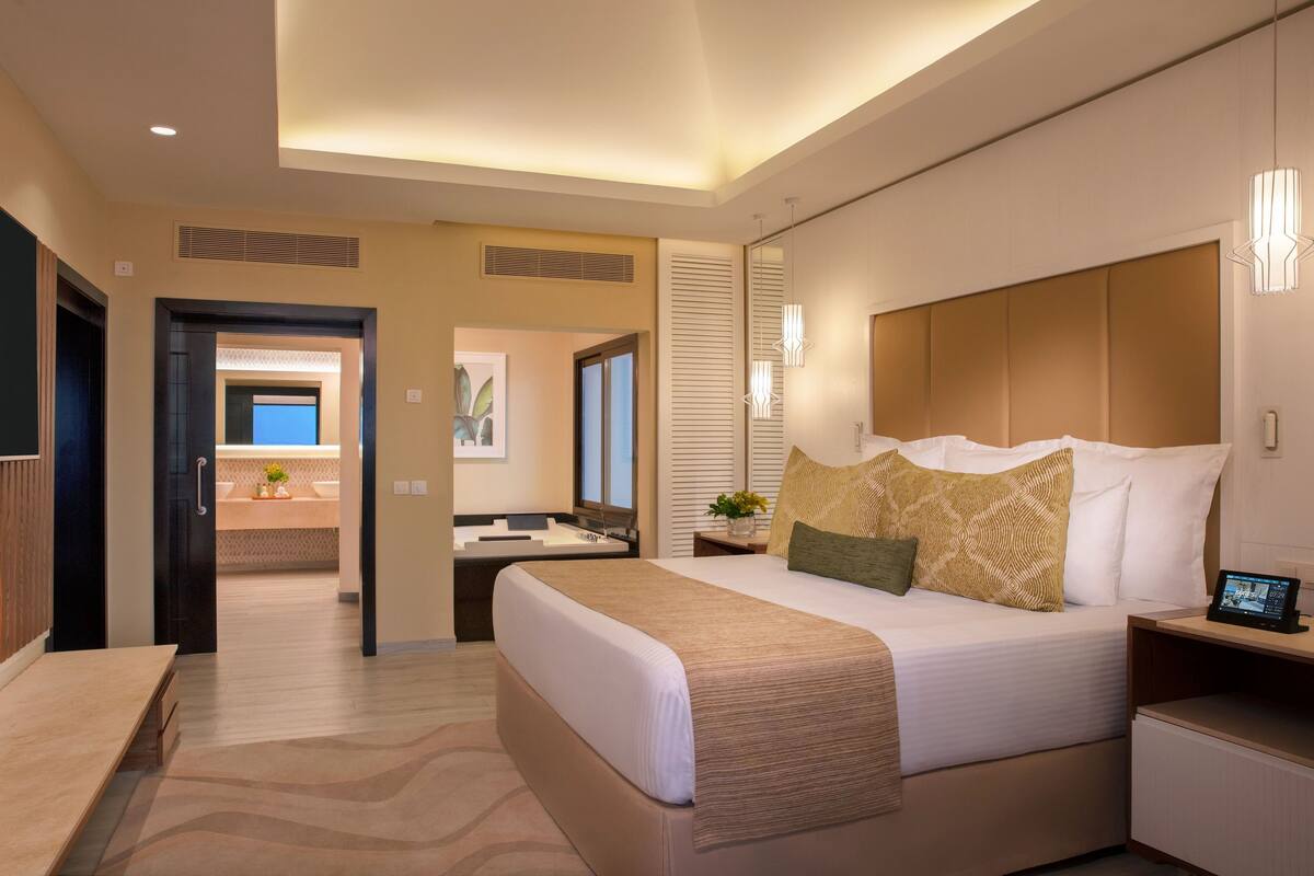 Ein modernes Hotelzimmer mit einem großen Bett, Nachttischen, einem Schreibtisch und einem Badezimmer mit Badewanne.