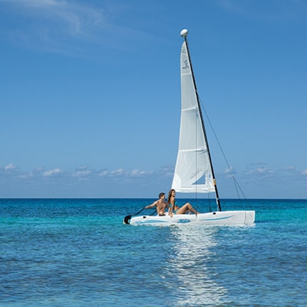 A sailboat with two people on the water.