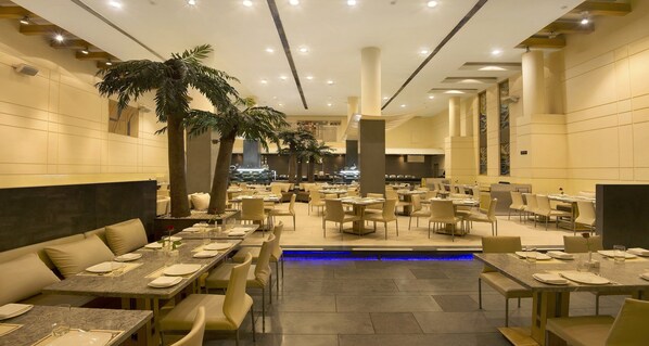 Um restaurante amplo com diversas áreas de refeição, incluindo cabines e mesas, e um elemento central de água.