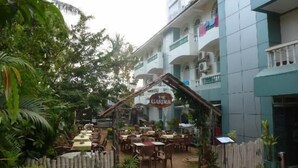 An outdoor dining area with tables and chairs, surrounded by a bamboo fence and potted plants. - La Ben Resort (Colva)