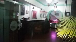 A reception area with a counter, framed pictures on the wall, and a ceiling fan. - La Ben Resort (Colva)