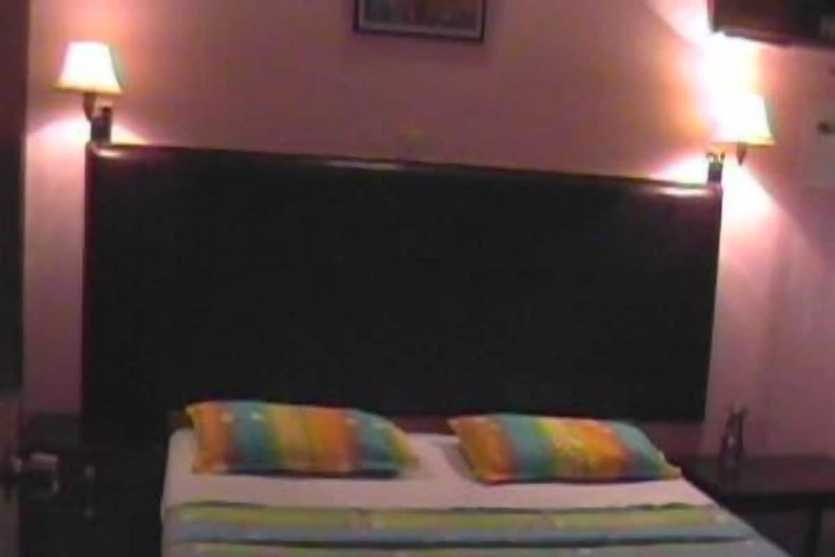 A bed with colorful striped bedding, two pillows, and two bedside lamps.