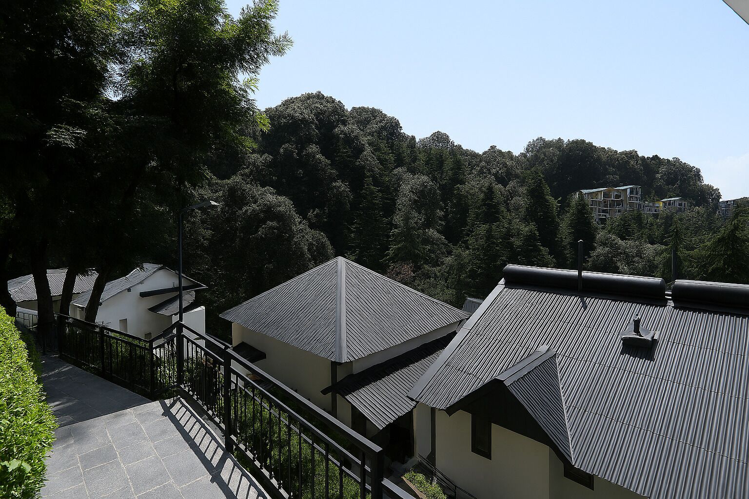 A residential area with houses featuring sloped roofs and a pathway leading to a gated entrance.