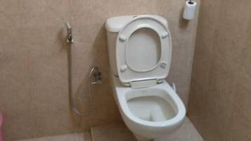 A bathroom with a toilet, a shower, and a toilet paper holder.