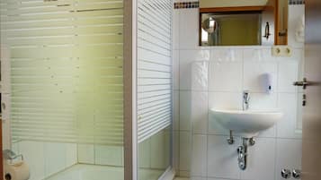 Een badkamer met douchecabine, toilet, wastafel en een vloer betegeld met blauwe tegels.