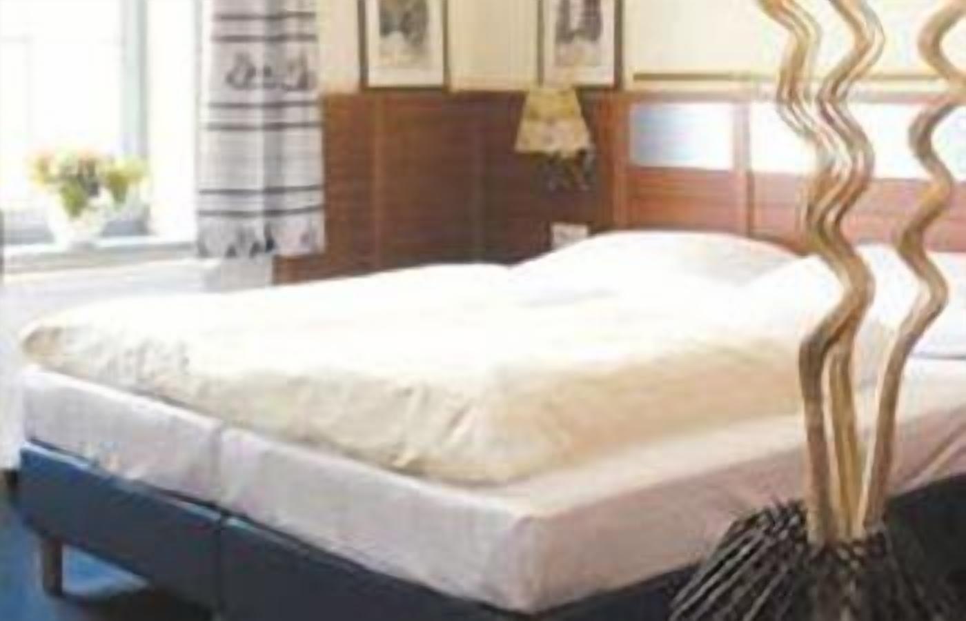 Un lit avec une tête de lit en bois, une table de chevet et une lampe.