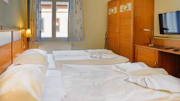 Una habitación de hotel con dos camas, televisión, escritorio y ventana con cortinas.