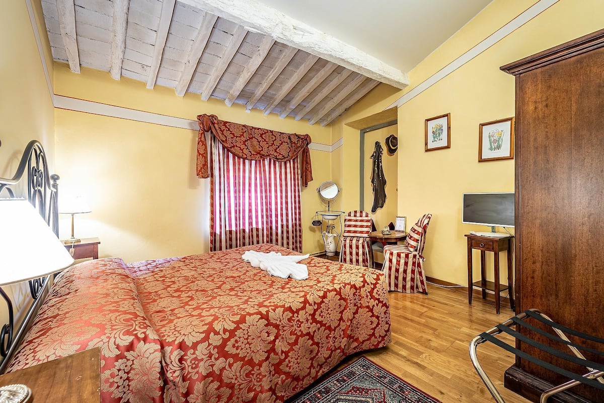 A bedroom with a bed, a desk, a chair, a TV, and a wardrobe.