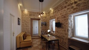 A dining area with a stone wall, a wooden table, and a sofa.