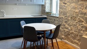 A modern kitchen with grey cabinets, a white countertop, and a round dining table with four chairs.