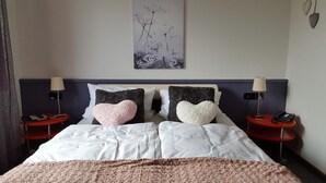 A neatly arranged hotel room with a large bed, two bedside tables with lamps, and a wall-mounted artwork. - Beauty & Wohlfühl Hotel (Syke)