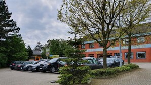 A parking lot with several cars, a building labeled "ARTEN HOTEL RESTAURANT," and a tree in the foreground. - Beauty & Wohlfühl Hotel (Syke)