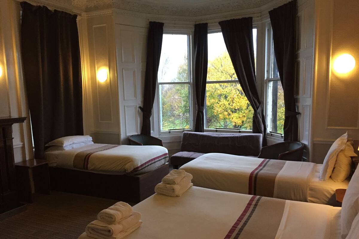 A hotel room with two beds, a desk, and a window with curtains.
