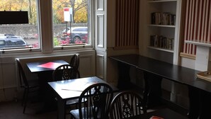 A room with a window, a bookshelf, and a table with chairs. - Edinburghhouse Hotel (Edinburgh)
