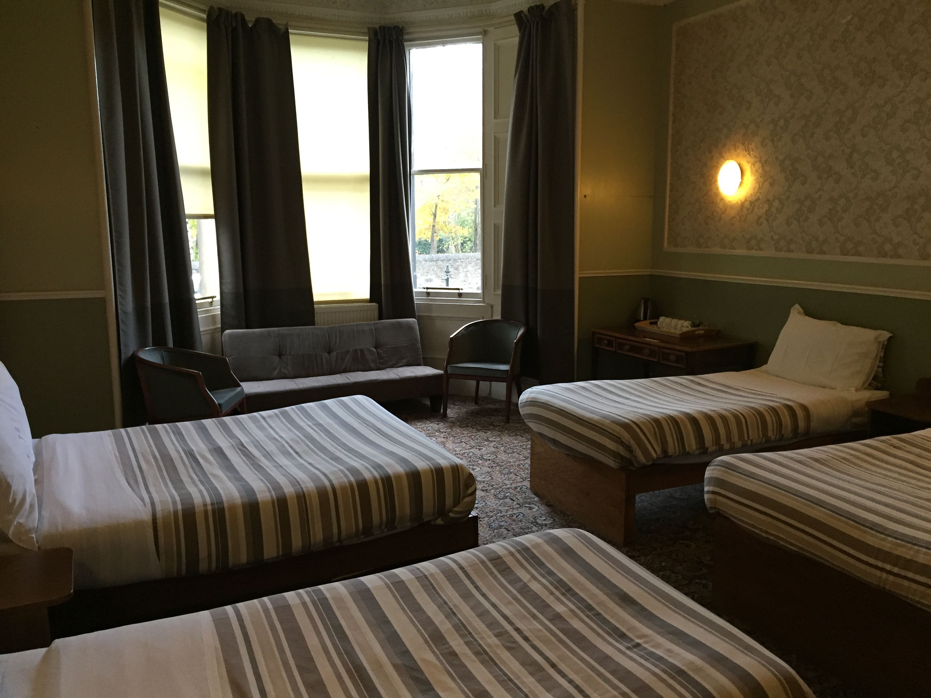 A hotel room with two single beds, a sofa, a chair, and a small table.