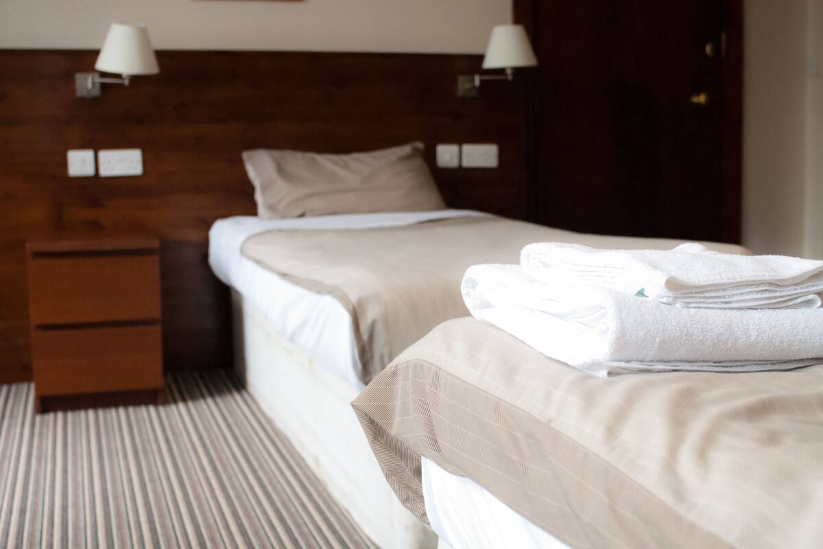 A hotel room with a bed, a nightstand, and a lamp.