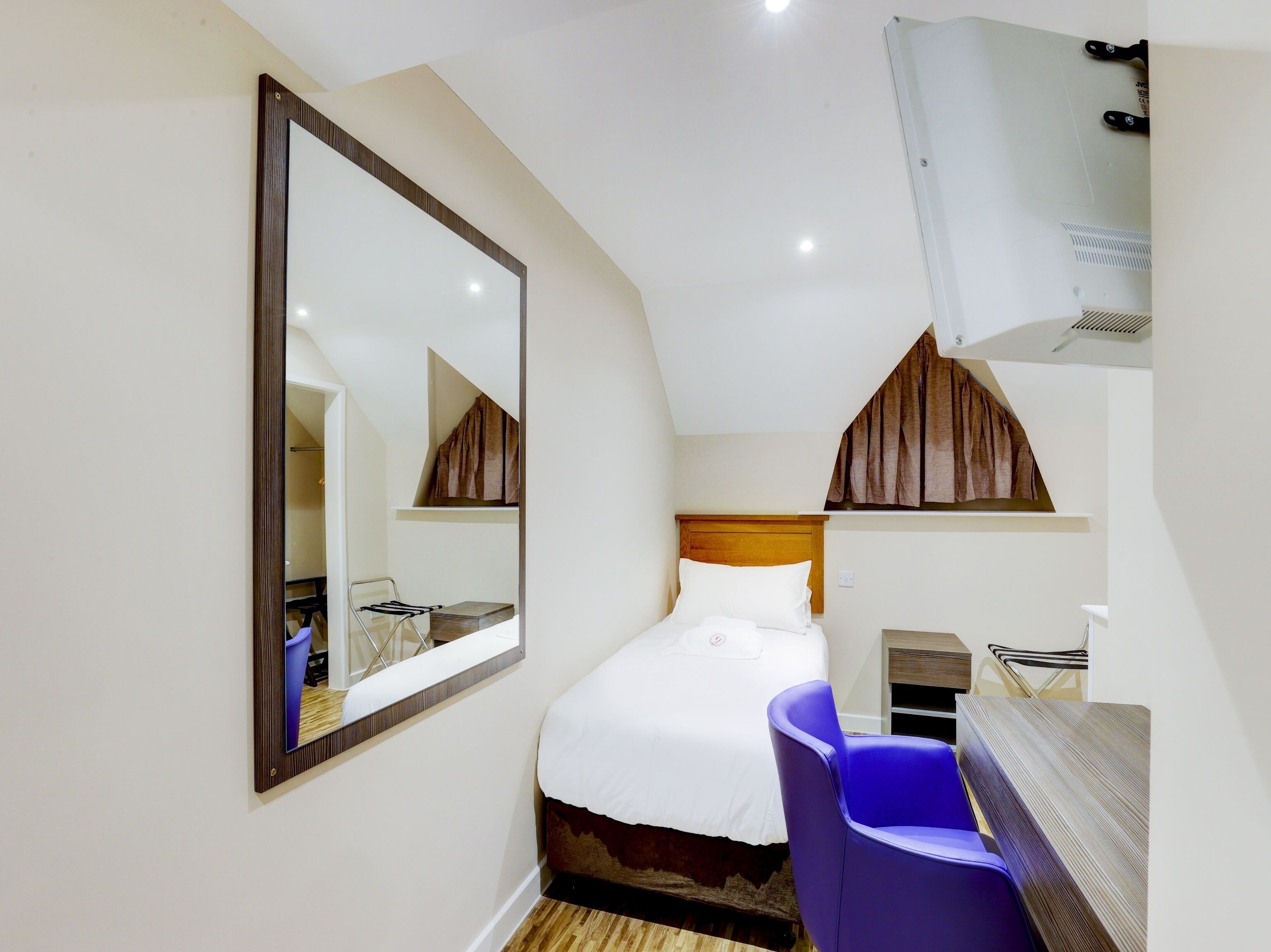 Une chambre à coucher comprenant un lit, une chaise, un bureau et un grand miroir.