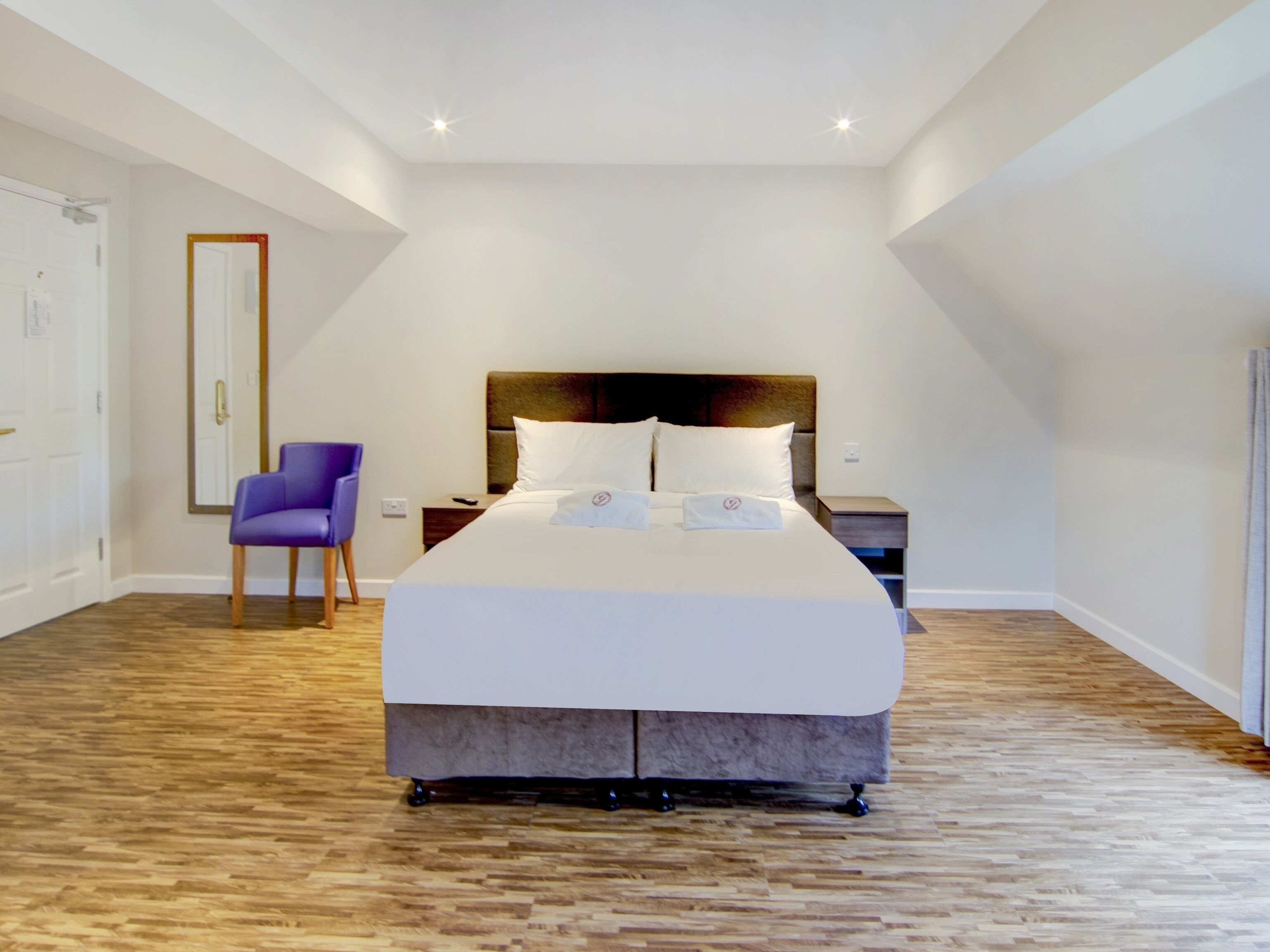 Un dormitorio moderno con una cama grande, una mesita de noche, una silla y una puerta.