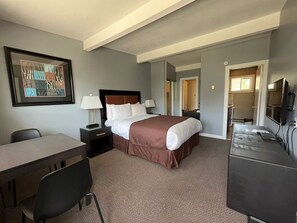 A hotel room with a large bed, a desk, a chair, a TV, and a framed picture on the wall. - Rondo Motel (Golden)