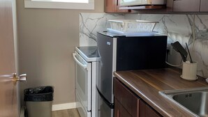 Une cuisine de taille réduite équipée d’un réfrigérateur, d’un four à micro-ondes et de meubles de rangement en bois.