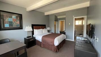 A hotel room with a bed, bedside tables, a desk, a chair, a TV, and a mirror.