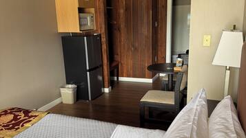 Habitación de hotel con cama, refrigerador, microondas, techo de madera y una pequeña mesa con una silla.