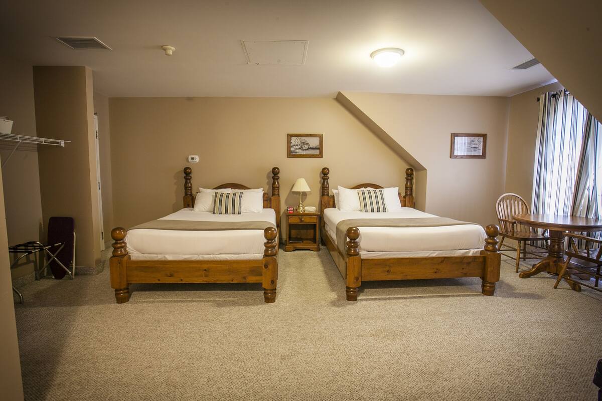 Une chambre d’hôtel avec deux lits en bois, une petite table et une chaise.