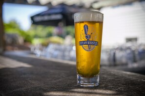 A tall glass of beer with a logo on it, placed on a table.